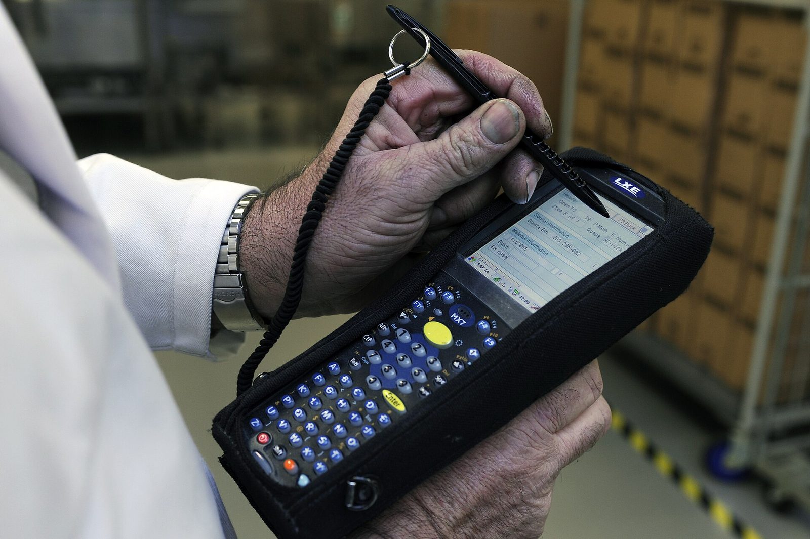 Operator care ține în mână un terminal mobil cu scanner de coduri și tastatură, folosit pentru urmărirea coletelor